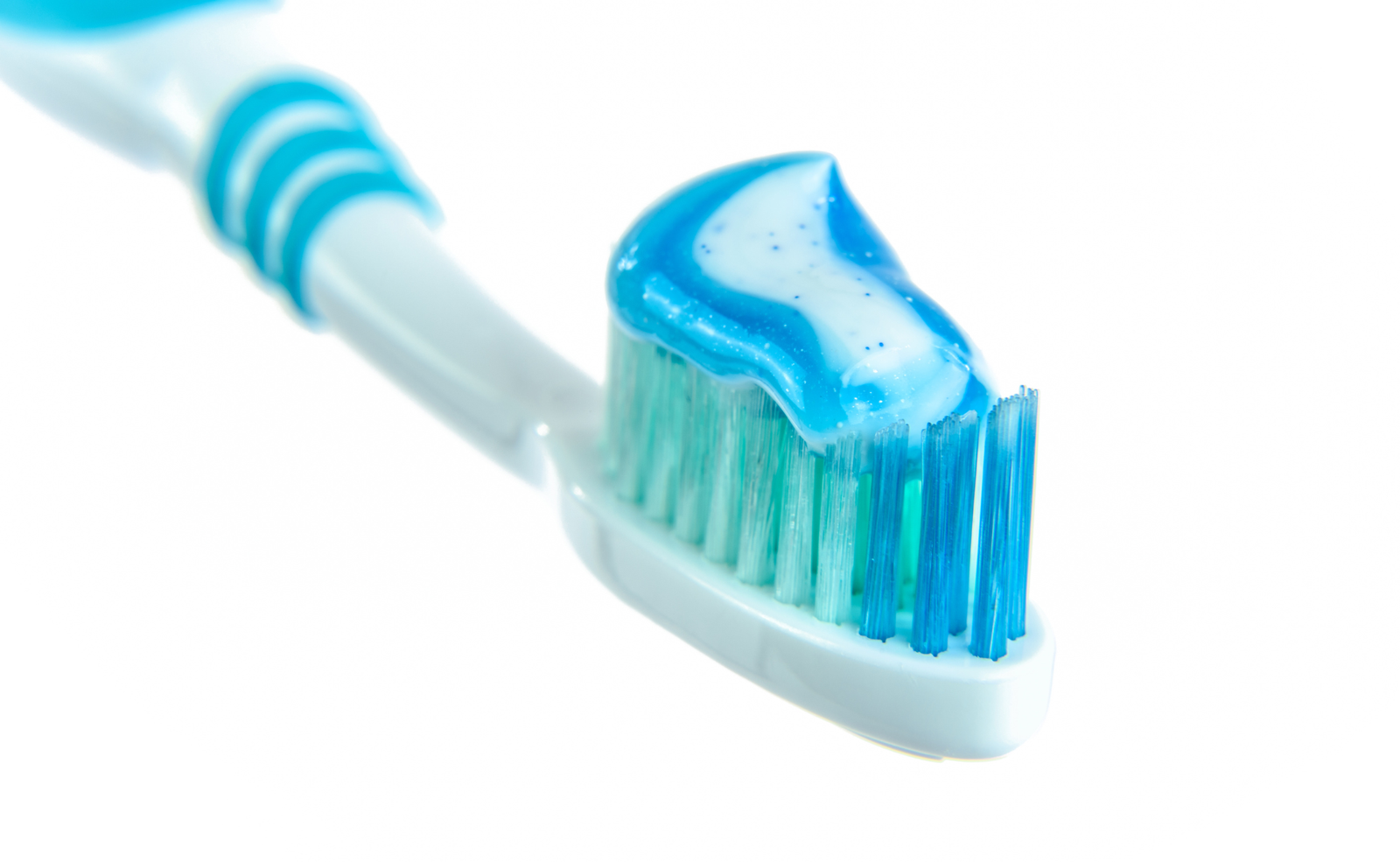 Cepillo de diente con pasta y fondo blanco